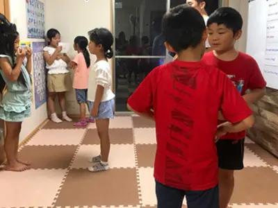 AES英会話のレッスンで、小学生がペアになって英語で会話練習をしている様子。実践的な英語力を身につける活動です。